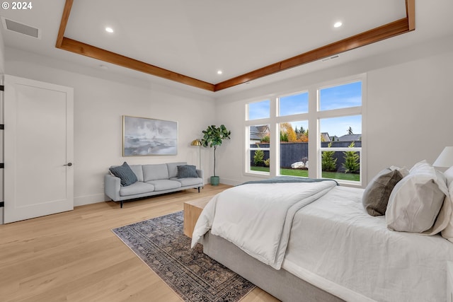 bedroom with light hardwood / wood-style floors and a tray ceiling