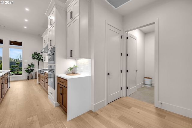 kitchen with oven, white cabinets, and light hardwood / wood-style floors