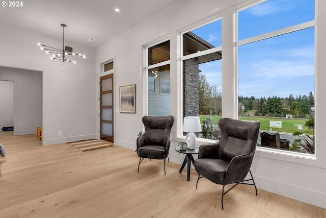 sitting room with plenty of natural light, a notable chandelier, and light hardwood / wood-style flooring