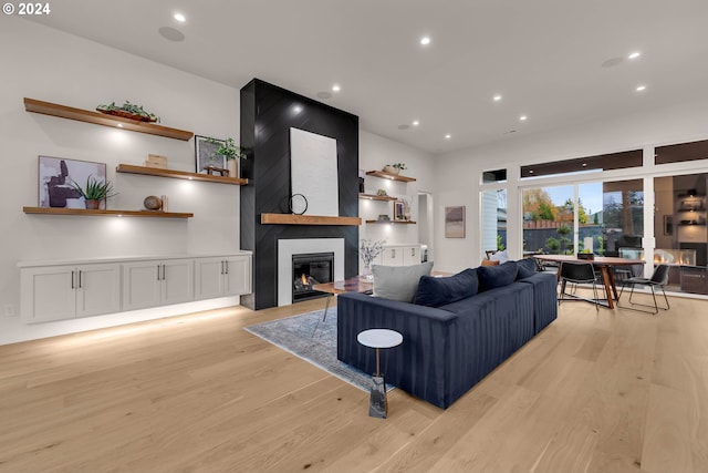 living room featuring light wood-type flooring and a large fireplace