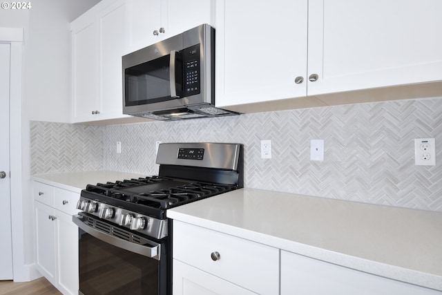 kitchen with light hardwood / wood-style flooring, white cabinets, tasteful backsplash, and stainless steel appliances