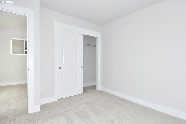 unfurnished bedroom featuring light carpet and a closet