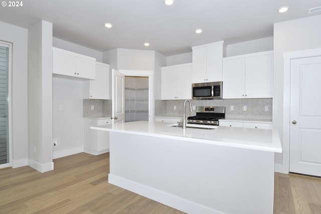 kitchen featuring light hardwood / wood-style flooring, appliances with stainless steel finishes, sink, and an island with sink