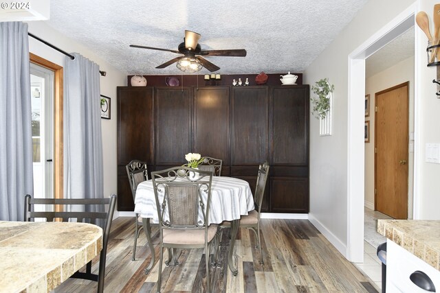 dining area featuring ceiling fan, wood-type flooring, and a textured ceiling