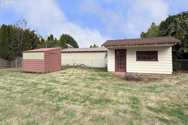 rear view of property with a storage unit and a lawn