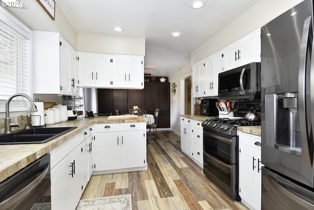 kitchen featuring stainless steel appliances, white cabinetry, sink, and light hardwood / wood-style flooring