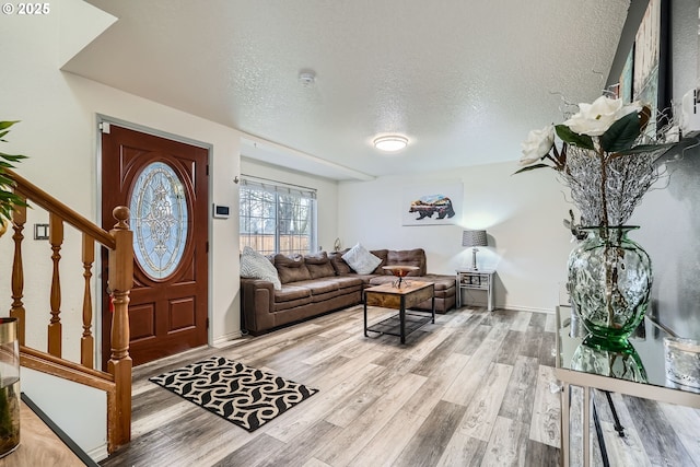 foyer with a textured ceiling, stairway, and light wood-style flooring