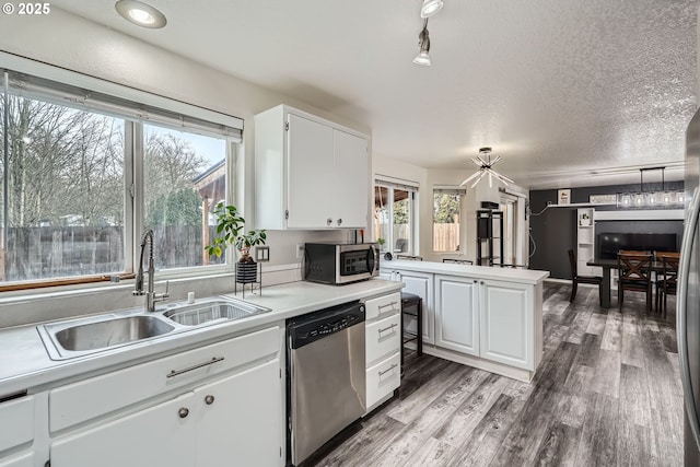 kitchen featuring a textured ceiling, a sink, light wood-style floors, light countertops, and appliances with stainless steel finishes