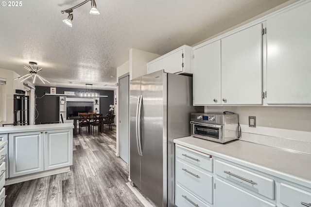 kitchen with wood finished floors, freestanding refrigerator, light countertops, a textured ceiling, and white cabinetry