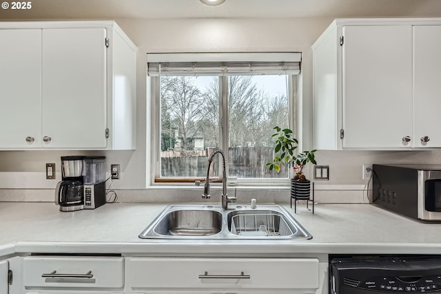 kitchen with white cabinets, dishwasher, light countertops, and a sink