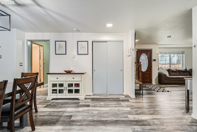 entrance foyer featuring a textured ceiling, baseboards, and wood finished floors