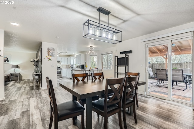 dining room featuring baseboards, light wood-style flooring, and a textured ceiling