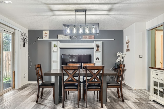 dining area featuring a textured ceiling, baseboards, and wood finished floors