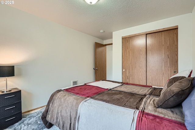 carpeted bedroom with a closet, visible vents, a textured ceiling, and baseboards