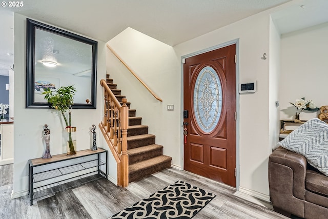 foyer with baseboards, stairway, and wood finished floors