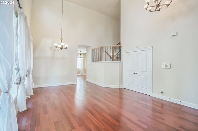 interior space featuring hardwood / wood-style flooring, a notable chandelier, and a high ceiling