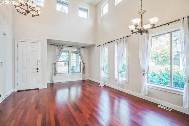 foyer with a towering ceiling, dark wood-type flooring, and an inviting chandelier