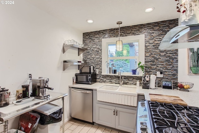 kitchen with tasteful backsplash, stainless steel appliances, decorative light fixtures, sink, and light hardwood / wood-style flooring