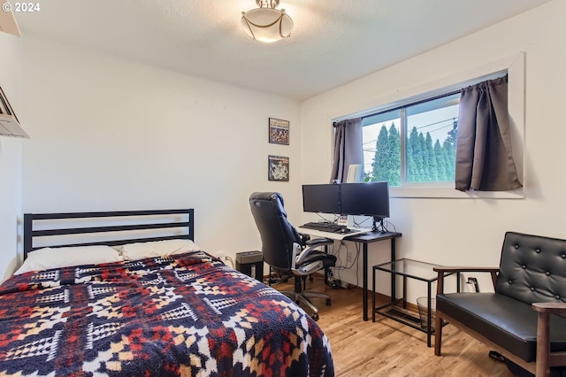 bedroom with a textured ceiling and light hardwood / wood-style floors