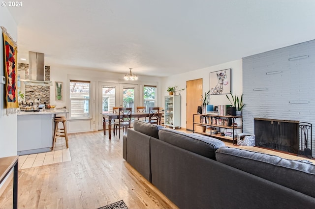 living room featuring light wood-type flooring, an inviting chandelier, and a large fireplace