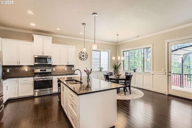 13632 SW 174th Loop, Sherwood, OR 97140 - kitchen featuring appliances with stainless steel finishes, a sink, dark countertops, plenty of natural light, and wainscoting