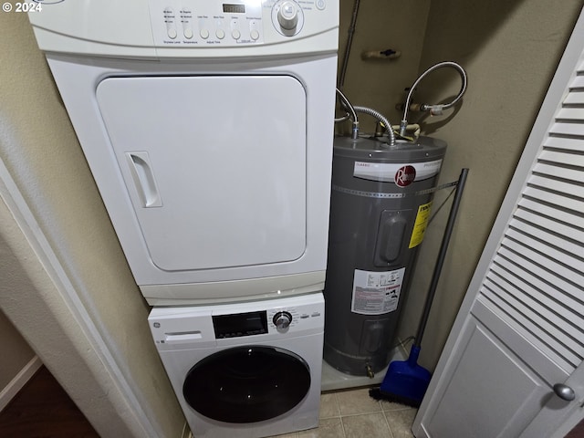 laundry room with electric water heater, stacked washer / dryer, and light tile patterned floors