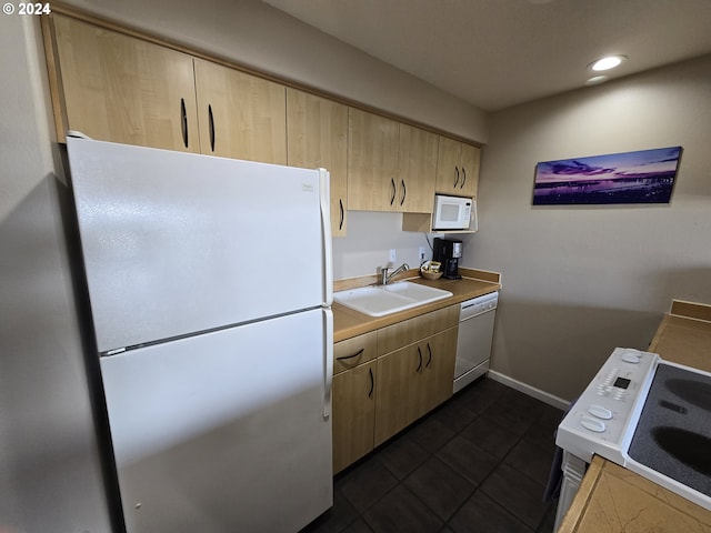 kitchen with light brown cabinetry, white appliances, and sink