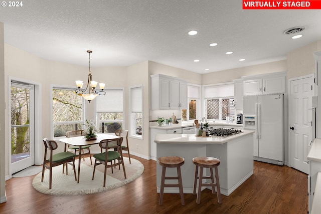 kitchen featuring a center island, white cabinets, dark hardwood / wood-style floors, and white refrigerator with ice dispenser