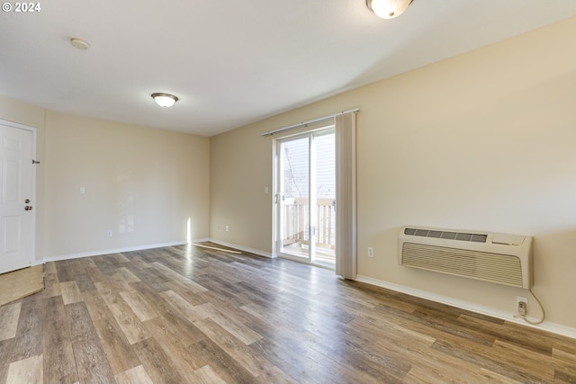 spare room featuring a wall mounted AC and light hardwood / wood-style floors