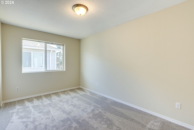 spare room with light carpet and a textured ceiling