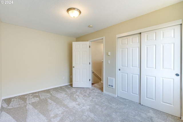 unfurnished bedroom featuring light carpet and a closet