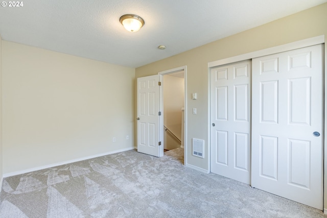 unfurnished bedroom with light colored carpet and a closet