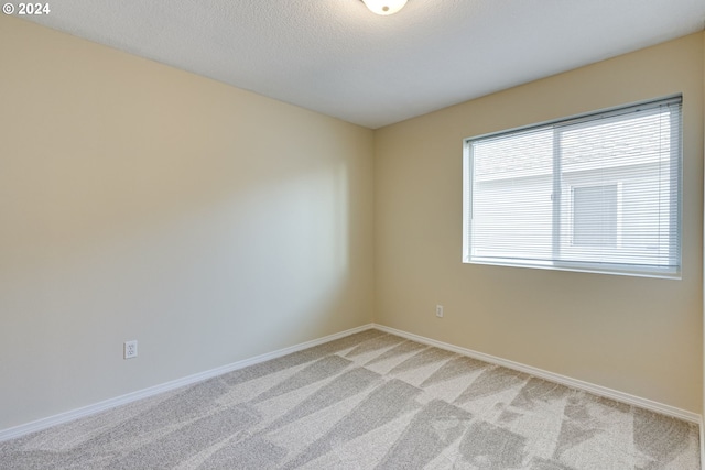 carpeted empty room with a textured ceiling