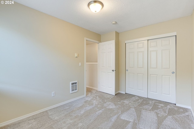 unfurnished bedroom with light carpet, a closet, a textured ceiling, and heating unit