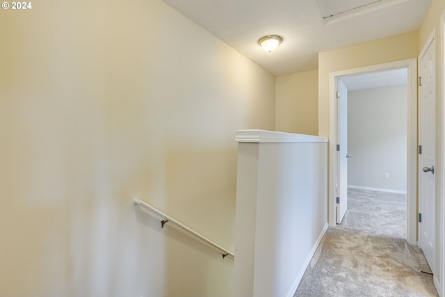 hallway featuring light carpet and a textured ceiling