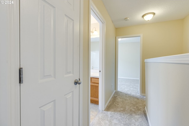 hall with light colored carpet and a textured ceiling