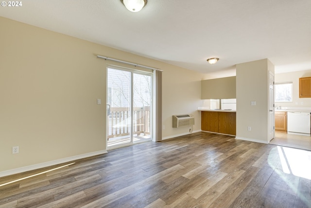 unfurnished living room featuring hardwood / wood-style floors and a wall mounted AC