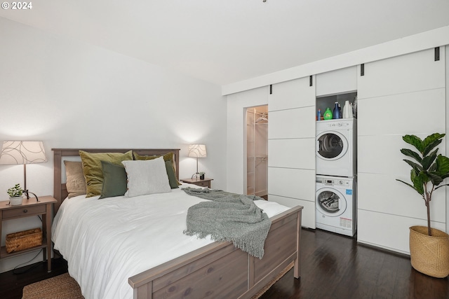 bedroom with stacked washer / dryer, dark hardwood / wood-style floors, a closet, and a walk in closet