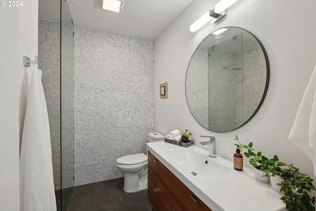 bathroom with vanity, toilet, and tiled shower