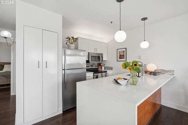 kitchen with kitchen peninsula, dark hardwood / wood-style floors, appliances with stainless steel finishes, decorative light fixtures, and sink