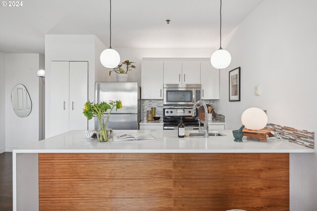 kitchen with appliances with stainless steel finishes, pendant lighting, decorative backsplash, and white cabinets