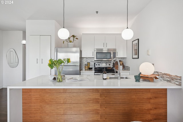 kitchen with white cabinets, stainless steel appliances, pendant lighting, and backsplash