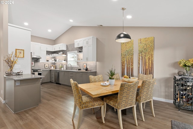 dining area featuring sink, light hardwood / wood-style flooring, and lofted ceiling