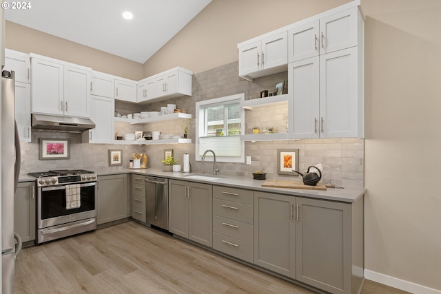 kitchen with sink, backsplash, vaulted ceiling, and stainless steel appliances