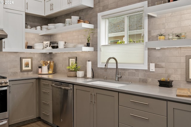 kitchen featuring tasteful backsplash, gray cabinets, stainless steel appliances, wood-type flooring, and sink