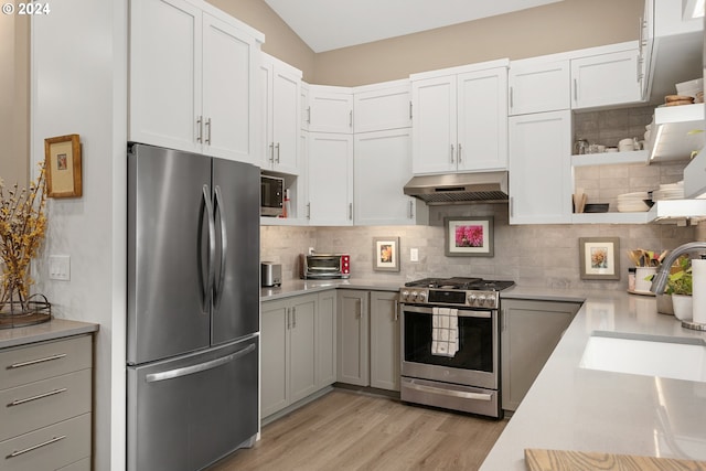 kitchen with decorative backsplash, light hardwood / wood-style flooring, stainless steel appliances, and wall chimney exhaust hood