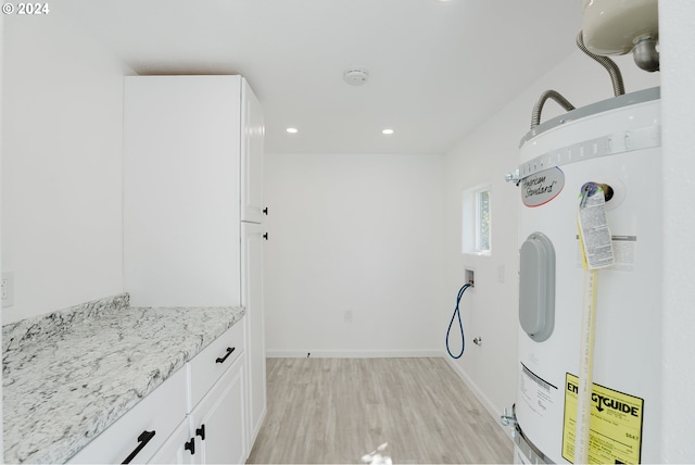 2840 Canyonville Riddle Rd, Riddle, OR 97469 - laundry room with electric water heater, baseboards, recessed lighting, light wood-style flooring, and cabinet space