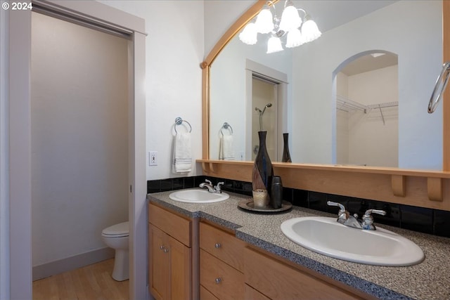 bathroom with hardwood / wood-style flooring, a notable chandelier, toilet, and vanity