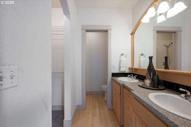 bathroom with wood-type flooring, vanity, toilet, and walk in shower