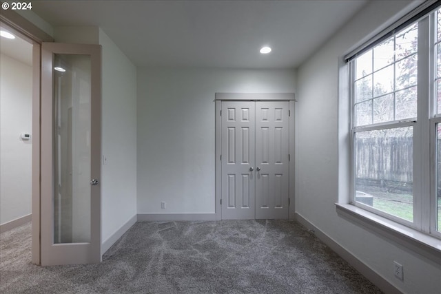 unfurnished bedroom with carpet flooring, multiple windows, and a closet